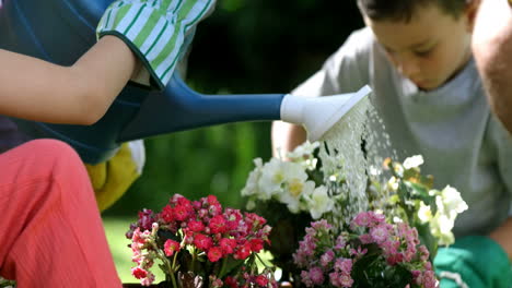 Close-up-on-a-cute-girl-is-watering-flowers-in-front-of-her-family-