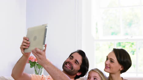 Cute-family-smiling-and-taking-a-photo-with-a-tablet