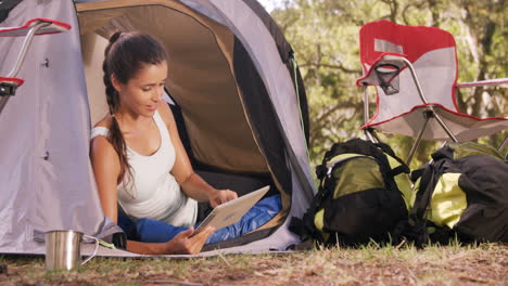 Woman-sitting-inside-the-tent-and-using-a-digital-tablet