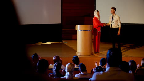 Multi-ethnic-business-people-shaking-hand-on-stage-in-business-seminar-at-auditorium-4k