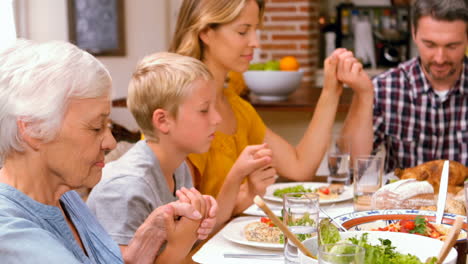 Cute-family-praying-before-eating-dinner