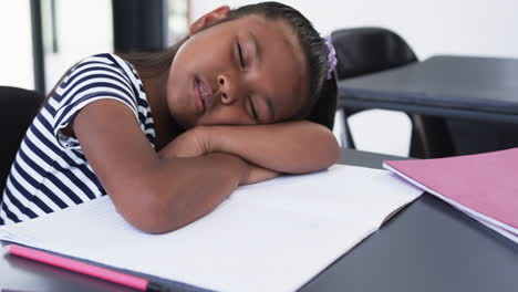 In-a-school-classroom,-a-young-biracial-girl-is-asleep-at-her-desk