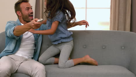 Happy-father-and-daughter-using-remote-on-the-sofa