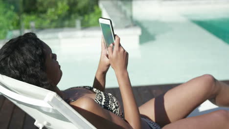 Mujer-Atractiva-Tumbada-En-Una-Tumbona-Usando-Un-Smartphone
