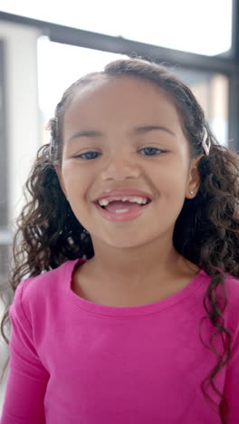 Vertical-video:-In-school,-young-biracial-girl-smiling-at-camera