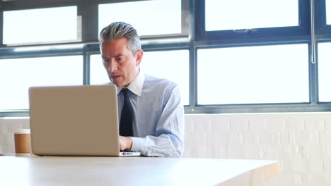 Businessman-using-laptop-and-drinking-coffee