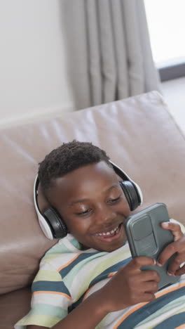 Vertikales-Video:-Afroamerikanischer-Junge-Trägt-Kopfhörer-Und-Hält-Smartphone