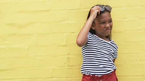 A-young-African-American-girl-stands-against-a-yellow-background-with-copy-space