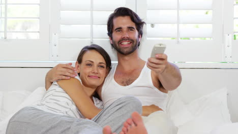 Cute-couple-lying-on-a-bed-and-looking-the-television