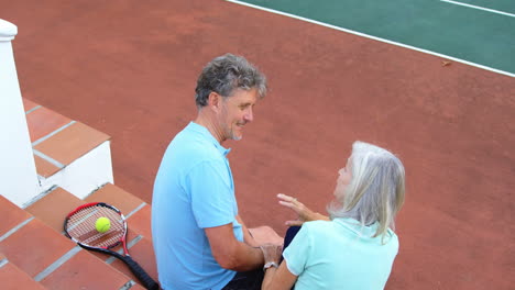 Pareja-Mayor-Sentada-En-Las-Escaleras-De-La-Cancha-De-Tenis-4k