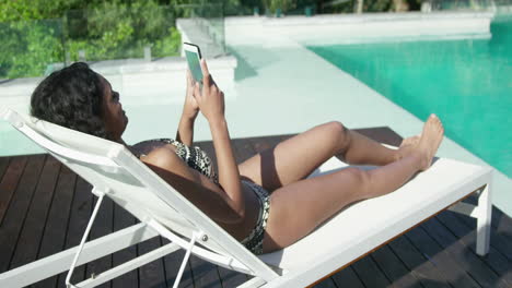 Mujer-Atractiva-Tumbada-En-Una-Tumbona-Usando-Un-Smartphone