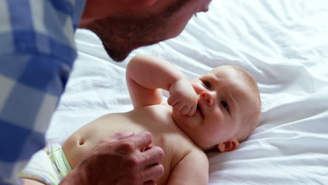 Father-playing-with-his-baby-lying-on-a-bed