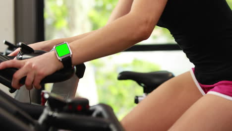 Mujer-En-Forma-Usando-Bicicleta-Estática-Y-Reloj-Inteligente.