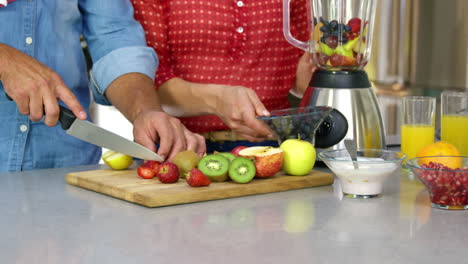 Couple-preparing-fruit-juice-on-the-kitchen