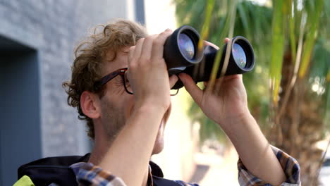 Young-hipster-is-looking-on-binoculars-and-smiling-