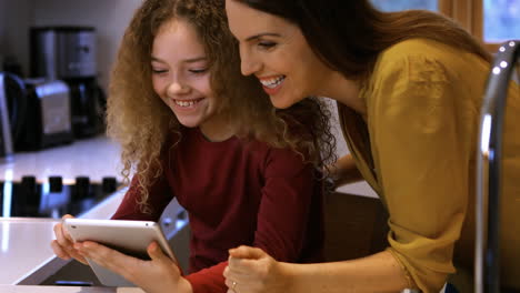 Daughter-and-mother-are-looking-a-tablet-on-a-bed-