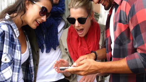 Casual-friends-wearing-sunglasses-and-using-smartphone