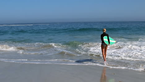 Mujer-Corriendo-Hacia-El-Agua-Con-Tabla-De-Surf