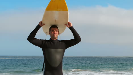 Man-in-wet-suit-holding-surfboard-over-head