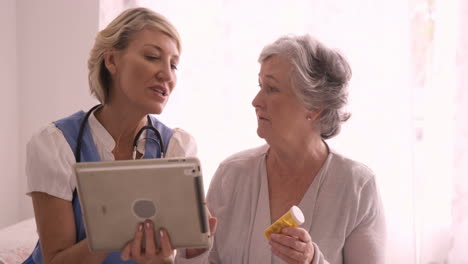 Female-doctor-showing-medical-report-to-senior-woman-on-digital-tablet