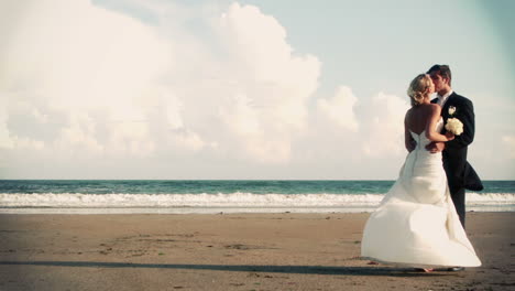Attractive-newlywed-couple-kissing-on-the-beach-in-cinemagraph