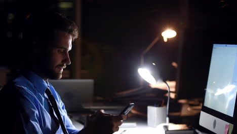 Businessman-using-smartphone-and-computer-at-night