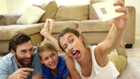 Glückliche-Familie-Liegt-Auf-Dem-Teppich-Und-Macht-Ein-Selfie