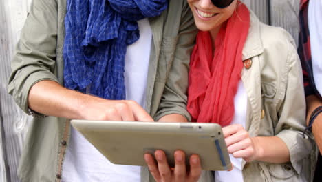 Casual-friends-wearing-sunglasses-and-using-tablet-pc