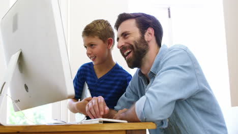 Happy-father-and-son-using-computer-together-