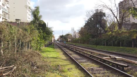 Establishing-shot-empty-train-tracks,-green-fields,-suburban-buildings-in-autumn