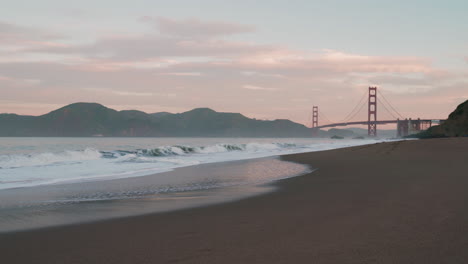 Atemberaubender-Sonnenaufgang-über-Der-Golden-Gate-Bridge-Mit-Meereswellen-Und-Wolken-Von-Baker-Beach,-San-Francisco