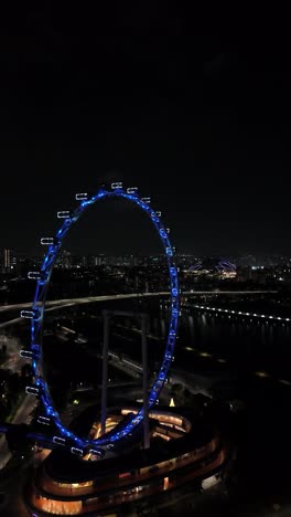 Singapore-Flyer-at-Night-in-Aerial-Approach-view,-vertical