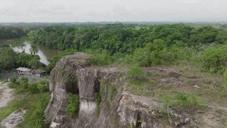 Rocky-cliffs-and-lush-greenery-by-a-river-in-florencia,-colombia,-aerial-view