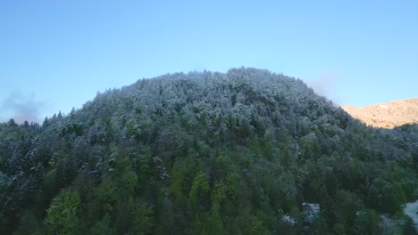 Schneebedeckter-Bewaldeter-Hügel-Unter-Klarem-Himmel,-Der-Den-Saisonalen-Übergang-Vom-Winter-Zum-Frühling-Markiert
