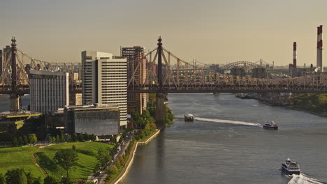 NYC-New-York-Luftaufnahme-Eines-V400-Drohnenüberflugs-Mit-Zoom-über-Den-East-River,-Der-Fähren-Auf-Dem-Wasserweg,-Den-Verkehr-Auf-Der-Queensboro-Bridge-Und-Die-Skyline-Von-Manhattan-Bei-Sonnenaufgang-Einfängt-–-Aufgenommen-Mit-Mavic-3-Pro-Cine-–-September-2023