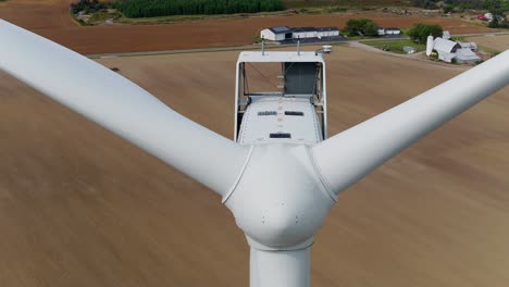 Wind-Turbine-Close-Up-Shot-with-Aerial-Drone-Ascending-Over-Wheat-Field-in-the-Background
