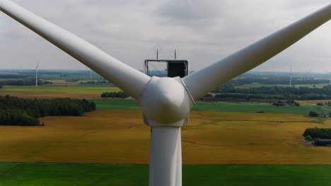 Wind-Turbine-Propeller-Blades-with-an-Aerial-View-Ascending-Overhead-and-Farmland-in-the-Background