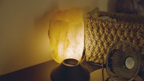 In-a-massage-room,-an-illuminated-salt-stone-lamp-is-positioned-close-up,-gently-reflecting-light-in-the-room