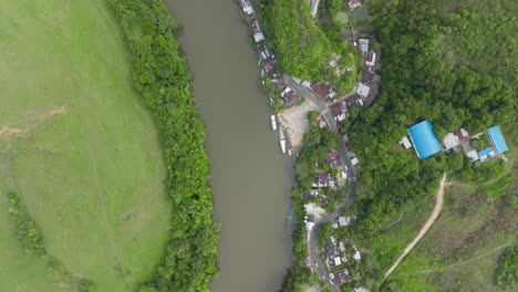 A-lush-riverbank-with-buildings-and-greenery-in-florencia,-colombia,-aerial-view