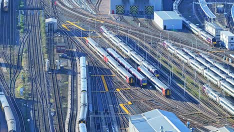 A-cinematic-shot-above-the-rail-tracks-loaded-with-passenger-diesel-and-electric-passenger-trains-parked-in-the-depot-at-Derby-railway-station,-England