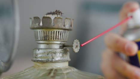 Spraying-Lubricant-On-Knob-Of-Old-Oil-Lamp