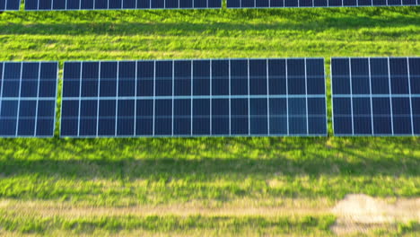 Low-aerial-flying-over-Solar-Panel-farm-on-a-green-field-in-golden-hour
