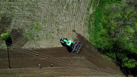 Aerial-view-of-chisel-plough-tractor-carving-furrows-in-fields,-tilling-soil