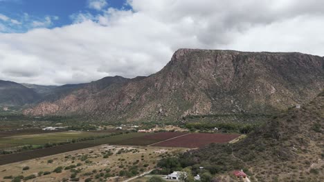 Vineyards-and-fields-beneath-rugged-mountains-in-Cafayate,-Salta,-Argentina-under-a-cloudy-sky