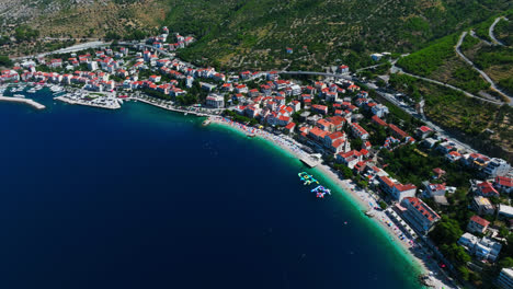 Aerial-view-circling-the-Podgora-town,-in-sunny-Makarska-riviera,-Croatia