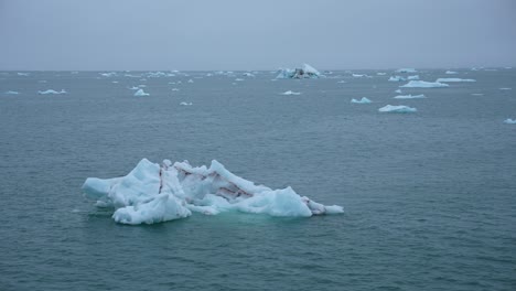 Sailing-in-Arctic-Sea-on-Cold-Misty-Day,-Icebergs-and-Pieces-of-Ice-in-Water,-Ship-Passenger-POV