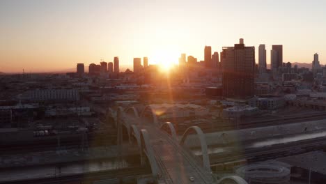 Aerial-reverse-pullback-panning-shot-of-the-Sixth-Street-Bridge-and-Viaduct-in-Los-Angeles,-California-at-sunset
