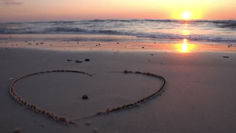 Herzsymbol-Auf-Sand-Gezeichnet-Vor-Dem-Hintergrund-Eines-Sonnenuntergangs-über-Dem-Meer