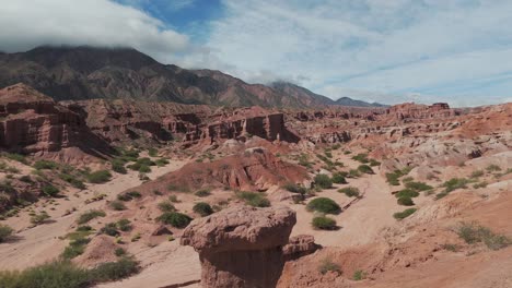 Man-exploring-the-stunning-red-rock-formations-in-Quebrada-de-las-Conchas,-Cafayate,-Argentina