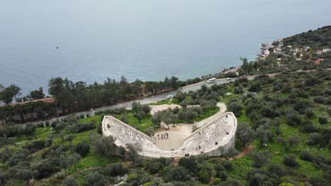 Fly-Up-Above-1st-Century-BCE-Ancient-Amphitheater-Overlooking-the-Mediterranean-Sea-Towards-Greek-Islands,-Antiphellos-Theatre-with-Coastal-View,-in-Kas,-Turkey:-Turkish-South-Coast